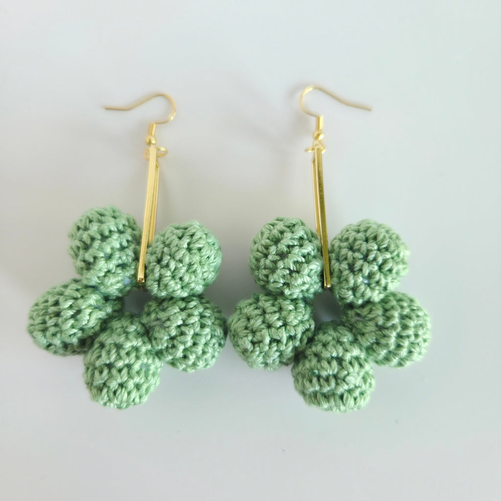 Green crocheted earrings with gold hooks on a white background