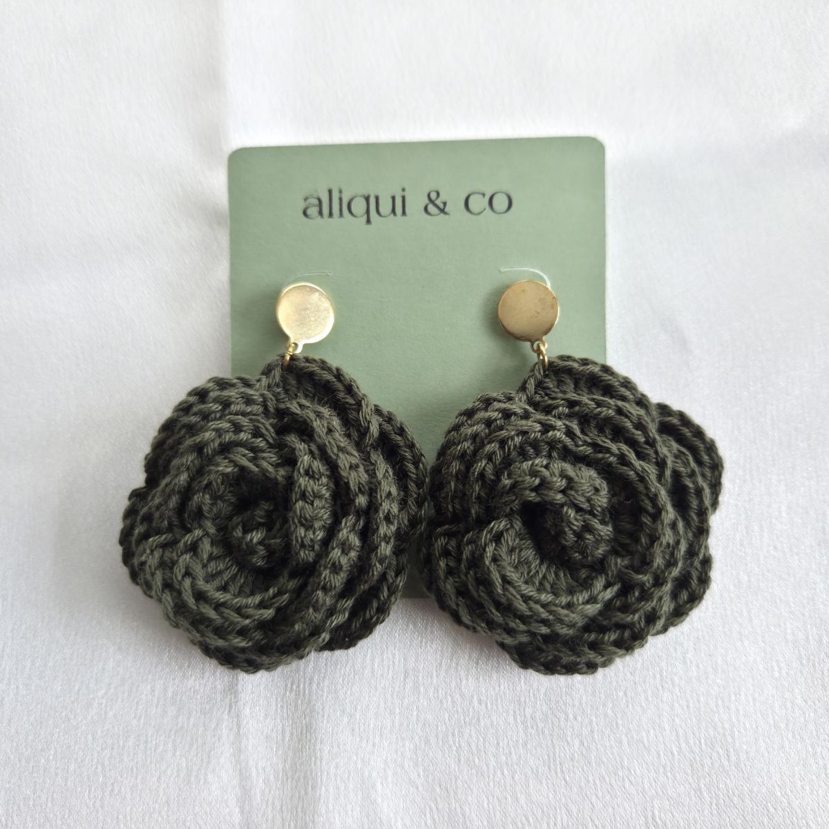 Pair of dark green knitted earrings on a 'aliqui & co' card against a white background